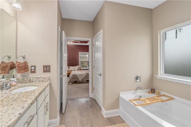 bathroom featuring vanity, hardwood / wood-style flooring, ceiling fan, and a tub