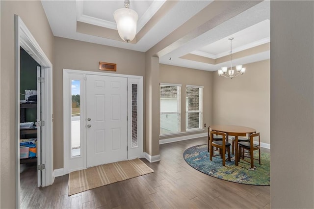 foyer featuring dark wood-type flooring, a healthy amount of sunlight, a tray ceiling, and a notable chandelier