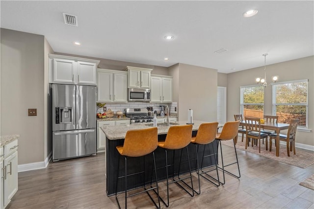 kitchen featuring a center island with sink, stainless steel appliances, decorative light fixtures, and sink