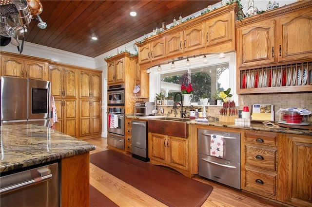 kitchen featuring stainless steel appliances, light hardwood / wood-style flooring, dark stone countertops, and ornamental molding