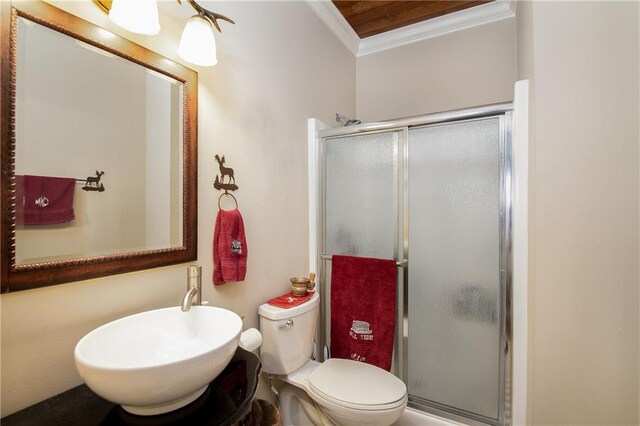 bathroom featuring a shower with shower door, toilet, ornamental molding, and sink