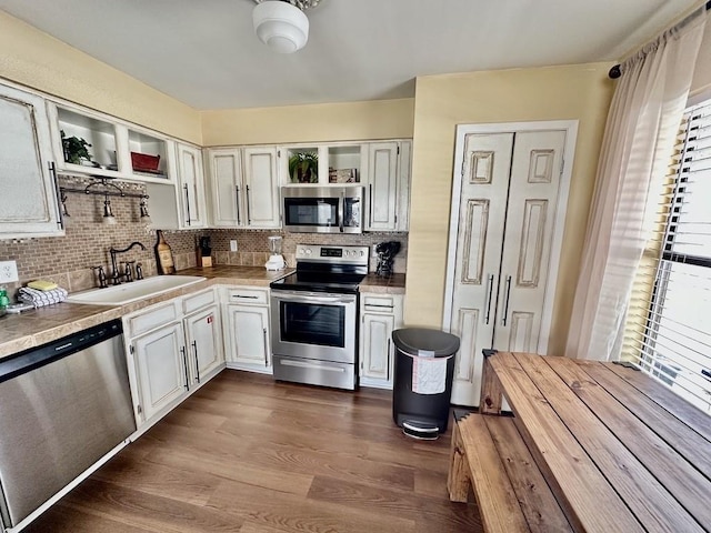 kitchen featuring tasteful backsplash, stainless steel appliances, dark hardwood / wood-style flooring, sink, and white cabinets