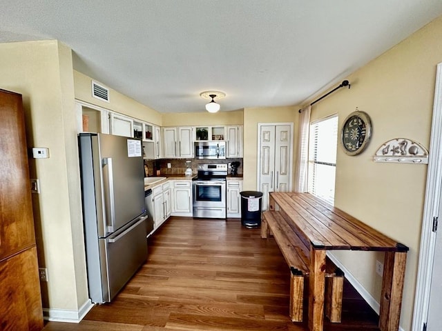 kitchen with backsplash, dark hardwood / wood-style floors, stainless steel appliances, and white cabinetry