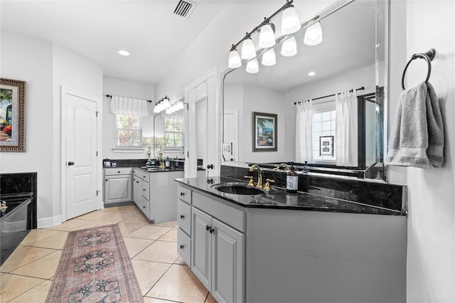 bathroom featuring a washtub, vanity, tile patterned flooring, and plenty of natural light