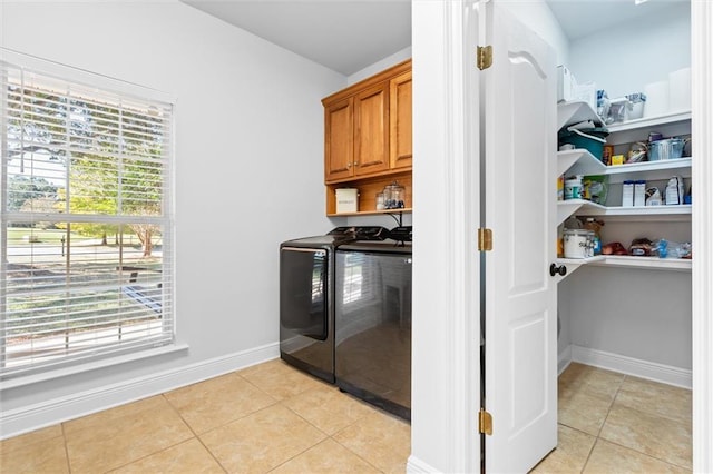 laundry room featuring cabinets, light tile patterned flooring, separate washer and dryer, and plenty of natural light