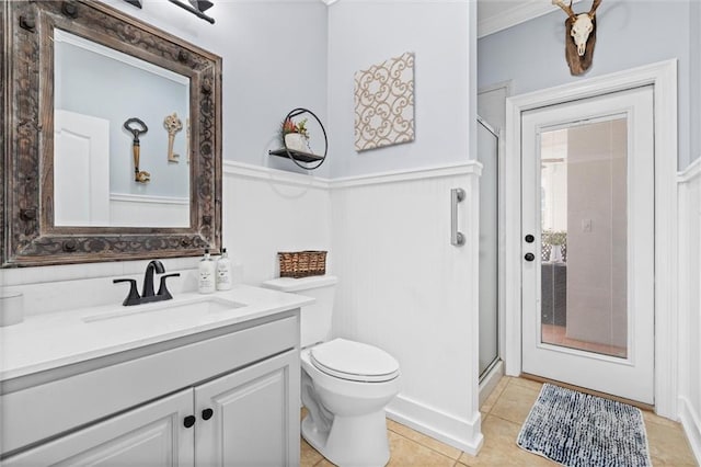 bathroom featuring a shower with door, toilet, tile patterned floors, vanity, and crown molding