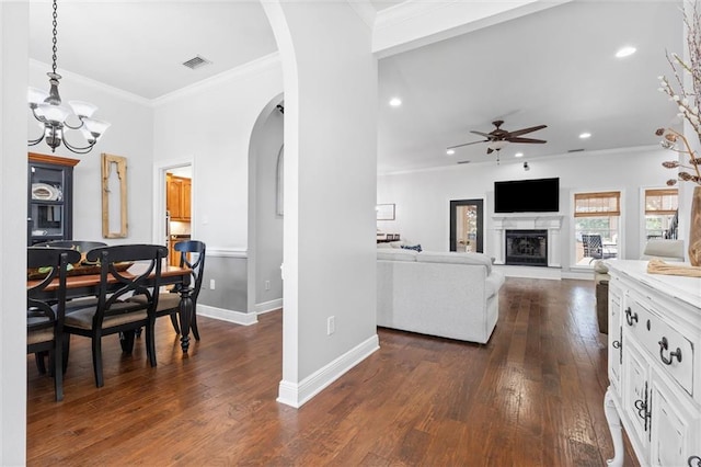 living room with crown molding, ceiling fan with notable chandelier, and dark hardwood / wood-style flooring