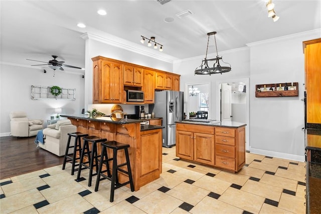 kitchen featuring a kitchen island, a breakfast bar area, stainless steel appliances, ornamental molding, and decorative light fixtures