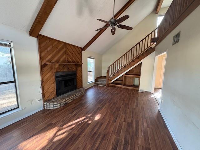 unfurnished living room featuring a fireplace, beam ceiling, dark wood-type flooring, and high vaulted ceiling