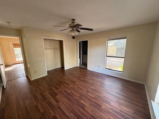 unfurnished bedroom featuring dark hardwood / wood-style flooring, multiple windows, a closet, and ceiling fan