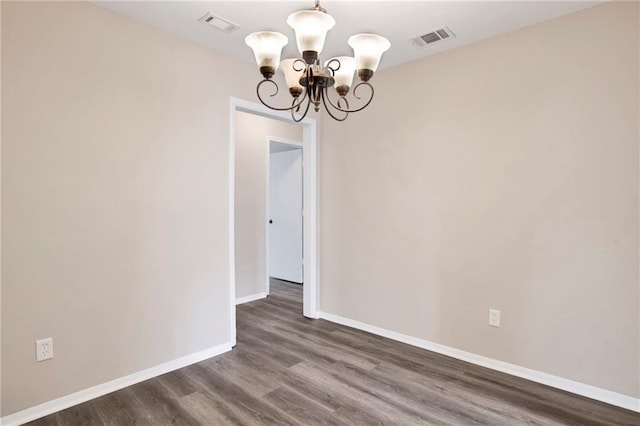 empty room featuring dark hardwood / wood-style floors and a chandelier