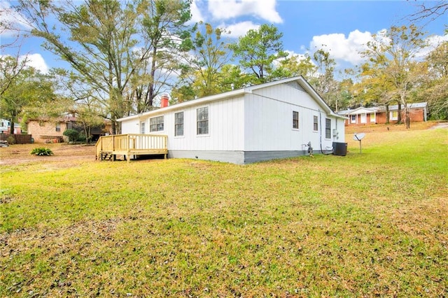 view of side of property featuring central air condition unit, a yard, and a wooden deck