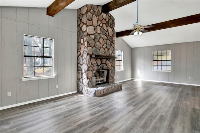 unfurnished living room with hardwood / wood-style flooring, ceiling fan, lofted ceiling with beams, and a stone fireplace