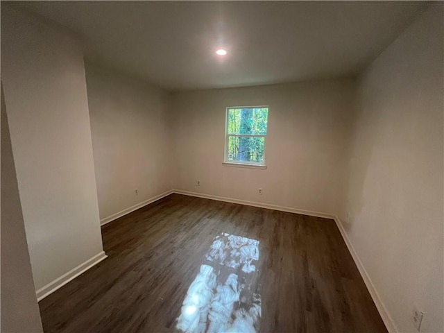spare room featuring baseboards, dark wood-type flooring, and recessed lighting