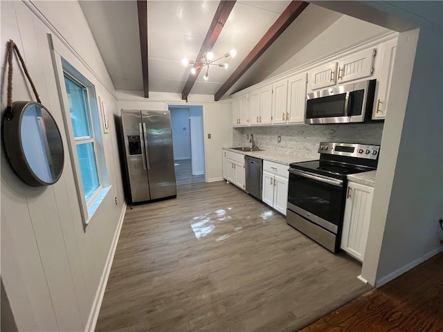 kitchen featuring lofted ceiling with beams, baseboards, a sink, and appliances with stainless steel finishes