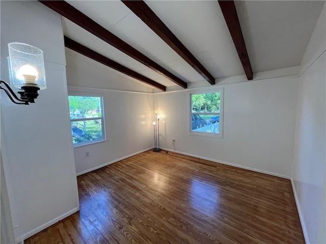 empty room with lofted ceiling with beams, baseboards, a healthy amount of sunlight, and wood finished floors