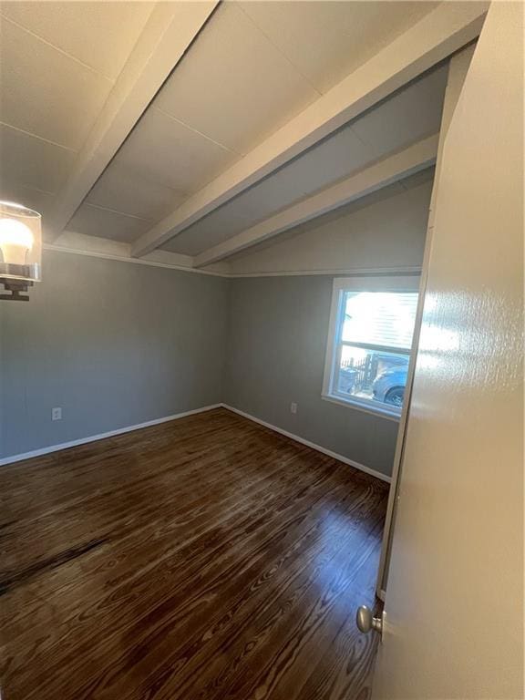 unfurnished room with lofted ceiling with beams, baseboards, and dark wood finished floors