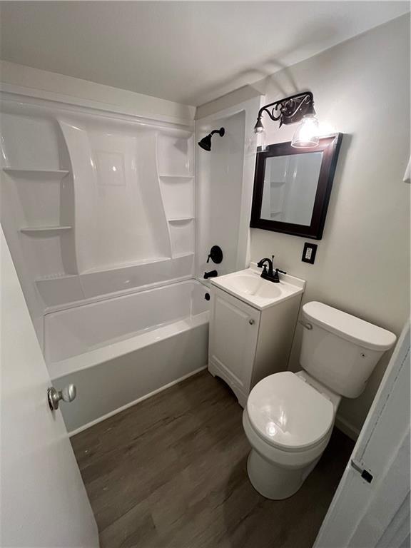 full bathroom featuring toilet, vanity, wood finished floors, and  shower combination