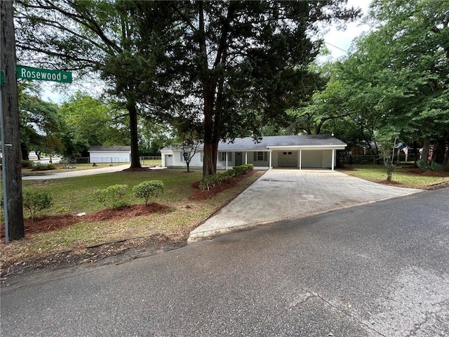 ranch-style house featuring fence, driveway, a front yard, and a carport
