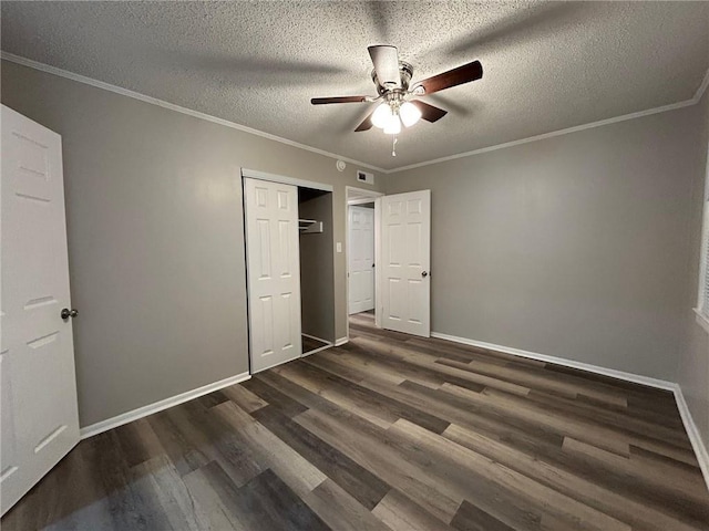 unfurnished bedroom with baseboards, ornamental molding, a textured ceiling, and dark wood-type flooring