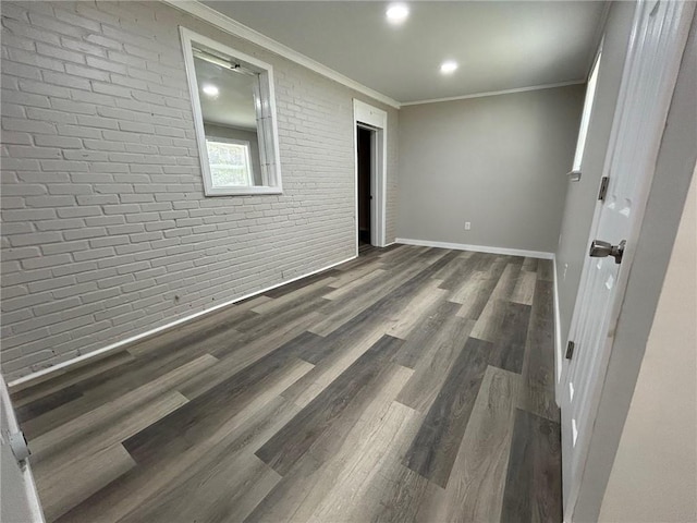 unfurnished room featuring brick wall, baseboards, recessed lighting, and wood finished floors