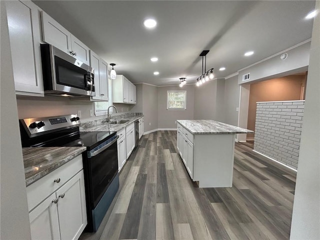 kitchen featuring a sink, stainless steel appliances, dark wood-type flooring, a kitchen island, and ornamental molding