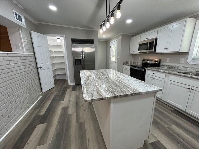 kitchen with visible vents, crown molding, a center island, light stone counters, and stainless steel appliances