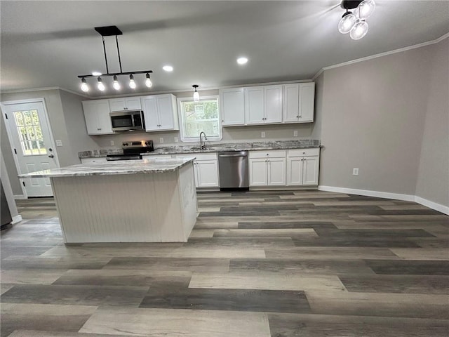 kitchen featuring a kitchen island, crown molding, appliances with stainless steel finishes, dark wood finished floors, and baseboards