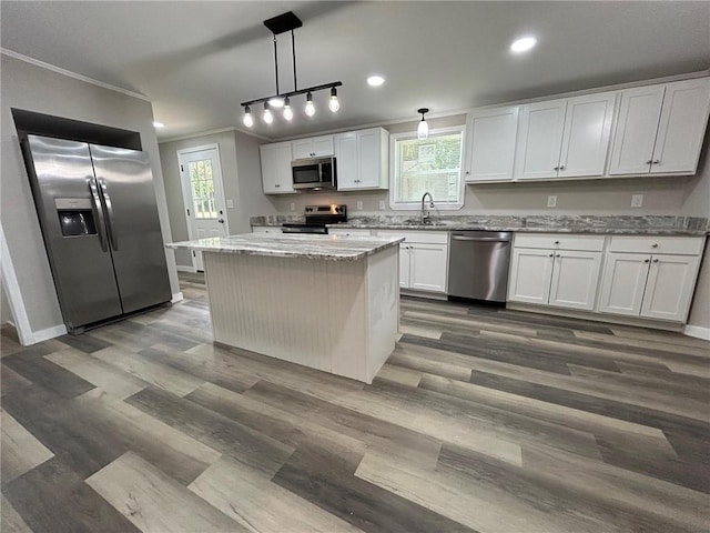 kitchen featuring a center island, ornamental molding, a healthy amount of sunlight, and stainless steel appliances