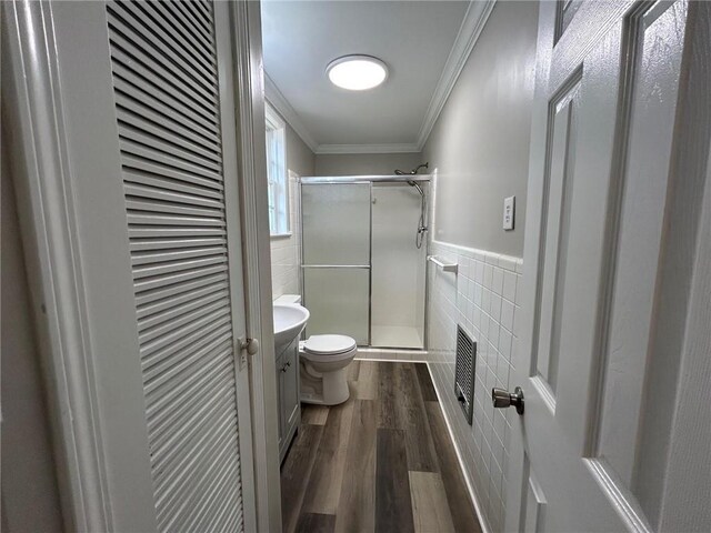 full bathroom featuring ornamental molding, wood finished floors, toilet, tile walls, and a stall shower