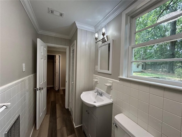 bathroom with visible vents, crown molding, wood finished floors, toilet, and tile walls
