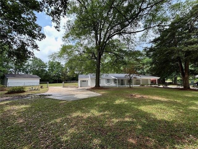 view of yard featuring fence, covered porch, concrete driveway, and a garage