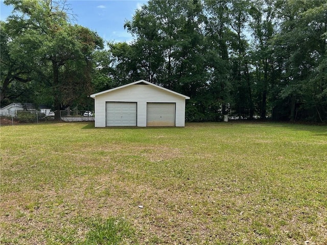 view of yard featuring a detached garage, fence, and an outbuilding