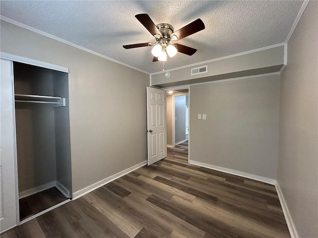 unfurnished bedroom with crown molding, a textured ceiling, visible vents, and dark wood finished floors