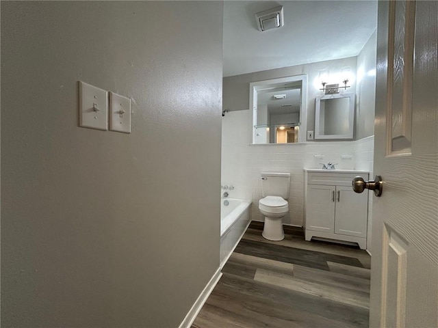 full bathroom featuring vanity, wood finished floors, toilet, tile walls, and shower / bathing tub combination