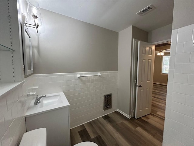 bathroom featuring tile walls, wood finished floors, visible vents, and vanity