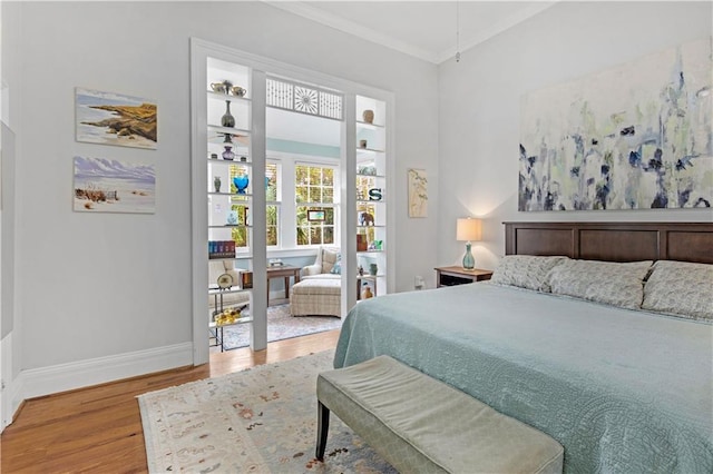 bedroom with crown molding, baseboards, and wood finished floors