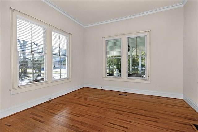 spare room with baseboards, visible vents, ornamental molding, and wood finished floors