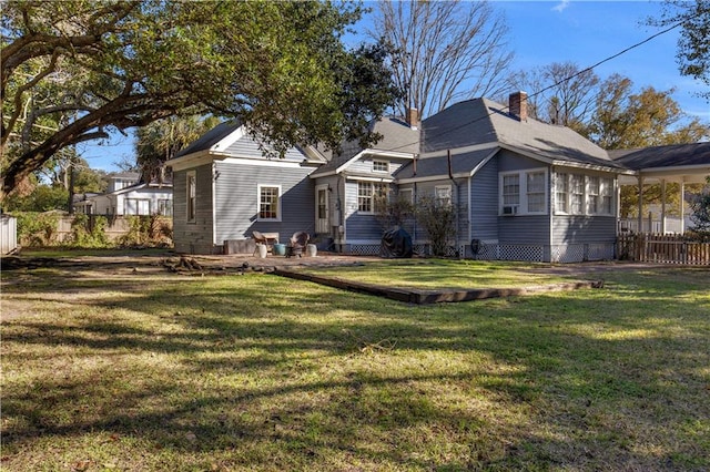 back of property featuring a yard, a chimney, and fence