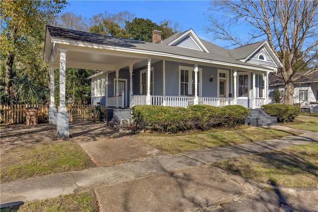 view of front of property featuring a chimney, fence, and a porch