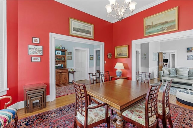 dining space featuring crown molding, a chandelier, and light wood-style floors