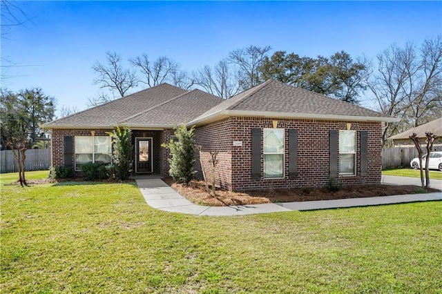 single story home featuring brick siding, a shingled roof, a front lawn, and fence