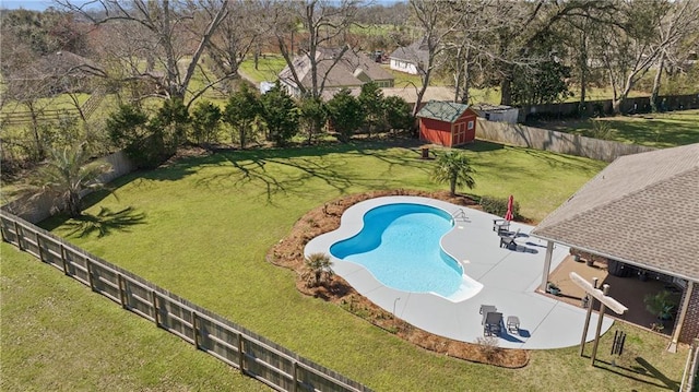 view of swimming pool featuring a storage unit, an outbuilding, a patio, a fenced backyard, and a yard