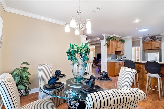 dining space featuring a chandelier, ornamental molding, and light hardwood / wood-style flooring