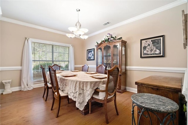 dining area featuring ornamental molding, a chandelier, and light hardwood / wood-style floors