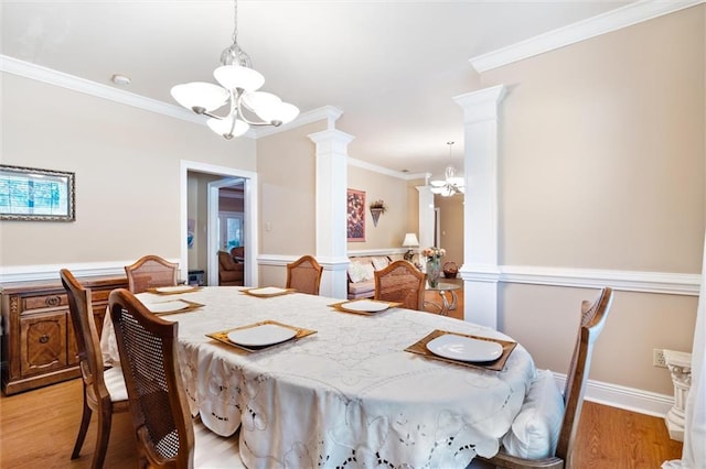 dining area featuring a chandelier, light wood-type flooring, decorative columns, and crown molding