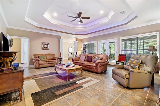 living room featuring decorative columns, a raised ceiling, ceiling fan, and crown molding