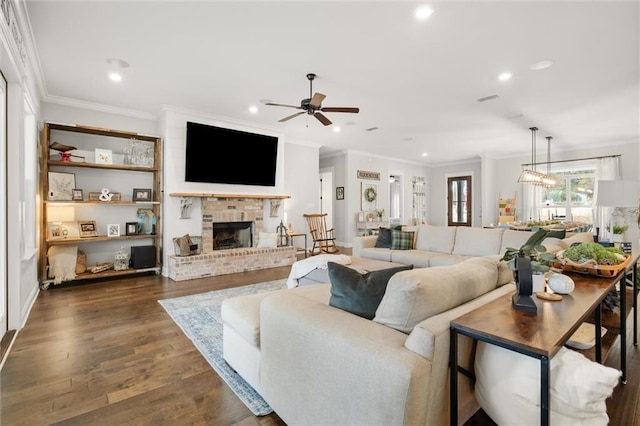 living room with dark hardwood / wood-style flooring, ceiling fan with notable chandelier, a fireplace, and ornamental molding