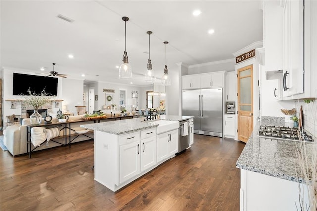 kitchen with sink, white cabinetry, a center island, appliances with stainless steel finishes, and pendant lighting