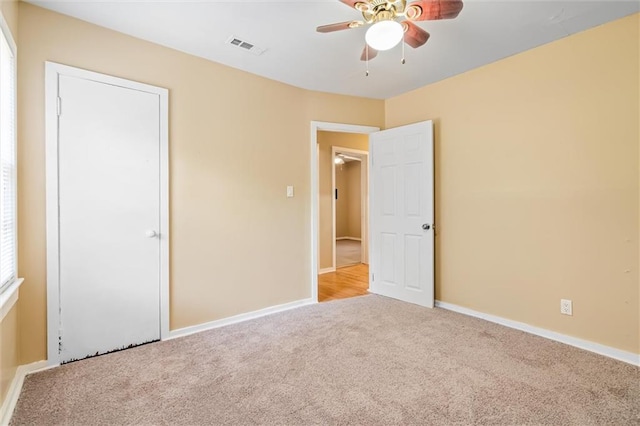 unfurnished bedroom with ceiling fan and light colored carpet